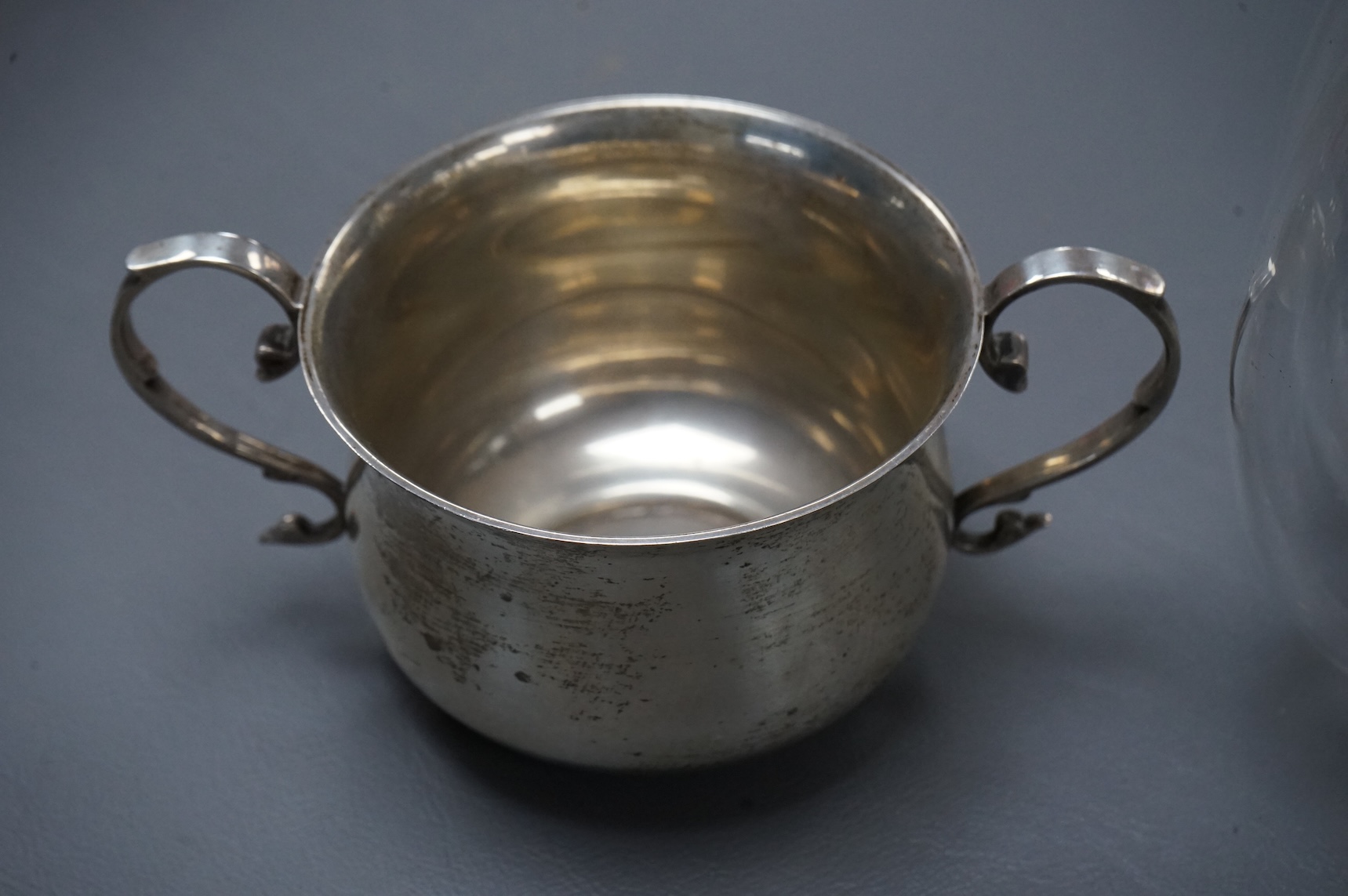 A late Victorian silver mounted lobed glass biscuit barrel by Hukin & Heath, with patent handle, London, 1899, height 14.4cm excluding the handle, together with a silver two handled condiment, a silver sugar bowl and a s